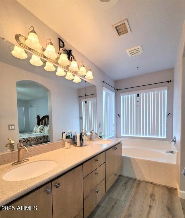 bathroom with tiled bath, vanity, and hardwood / wood-style flooring