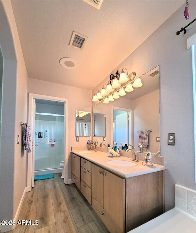 bathroom featuring walk in shower, hardwood / wood-style floors, a textured ceiling, toilet, and vanity