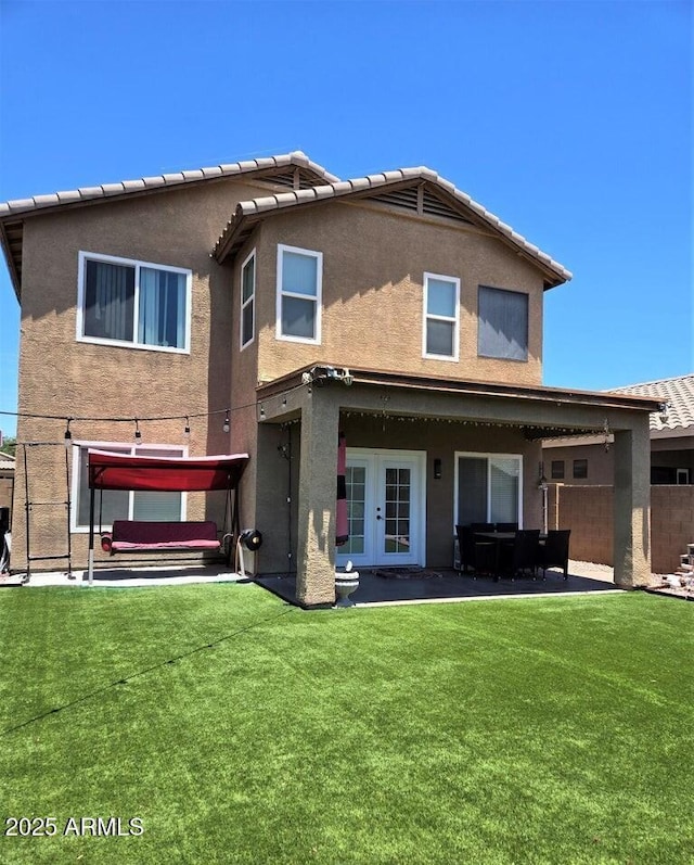 back of house with french doors, a patio area, and a lawn