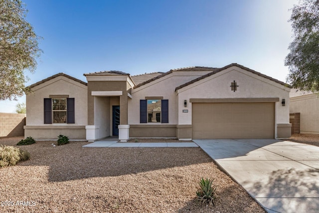 view of front of house featuring fence, a garage, stucco siding, a tiled roof, and driveway