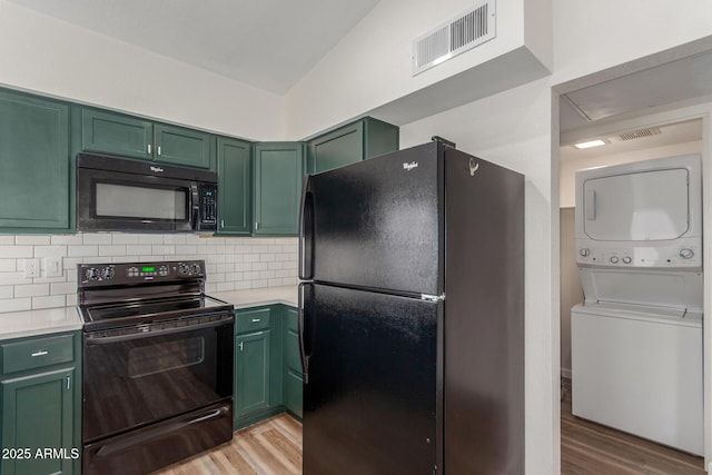 1047 W Laguna Dr, Tempe, AZ 85282 - kitchen with black appliances, green cabinetry, stacked washer / drying machine, light countertops, and light wood-type flooring