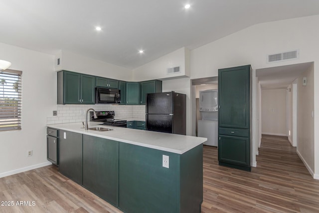 1047 W Laguna Dr, Tempe, AZ 85282 - kitchen featuring black appliances, lofted ceiling, stacked washer / dryer, a sink, and wood finished floors