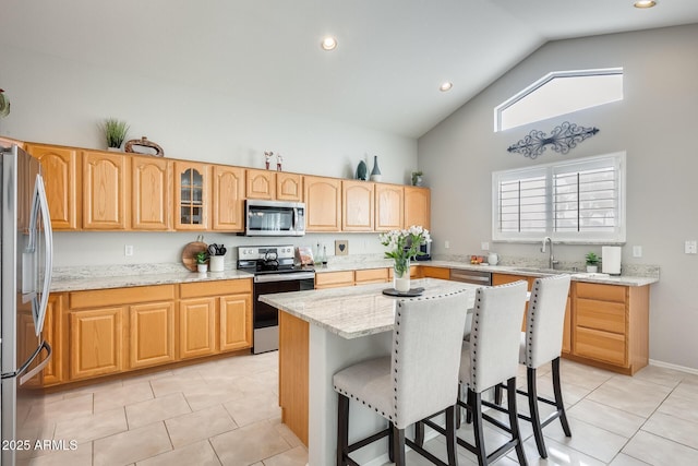 kitchen with light stone countertops, appliances with stainless steel finishes, a center island, and light tile patterned flooring