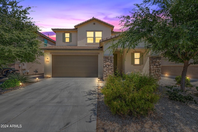 view of front of home with concrete driveway, stone siding, an attached garage, and stucco siding