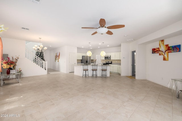 living room featuring light tile patterned flooring and ceiling fan with notable chandelier