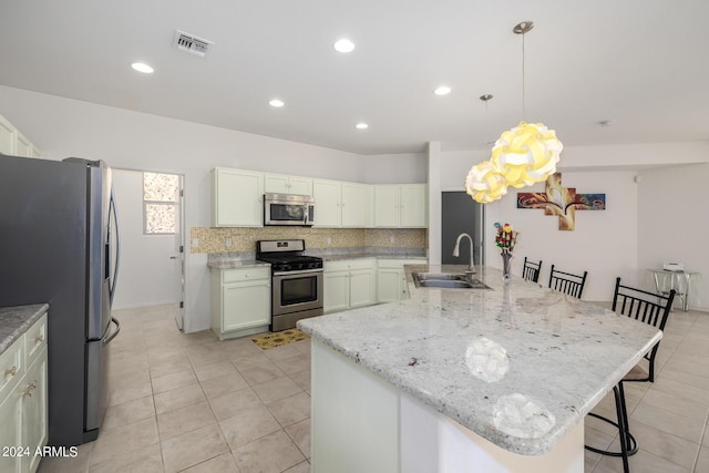 kitchen featuring a breakfast bar area, stainless steel appliances, a sink, visible vents, and hanging light fixtures