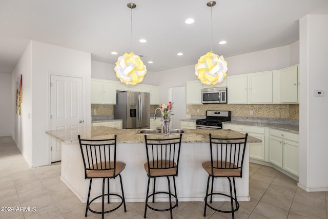 kitchen with appliances with stainless steel finishes, a center island with sink, and decorative light fixtures