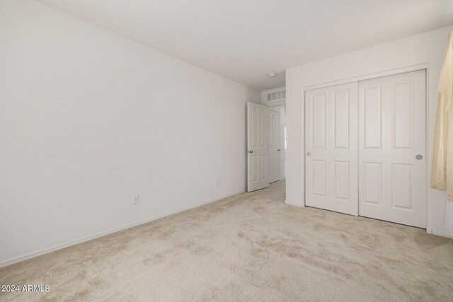 unfurnished bedroom with connected bathroom, light colored carpet, and ceiling fan