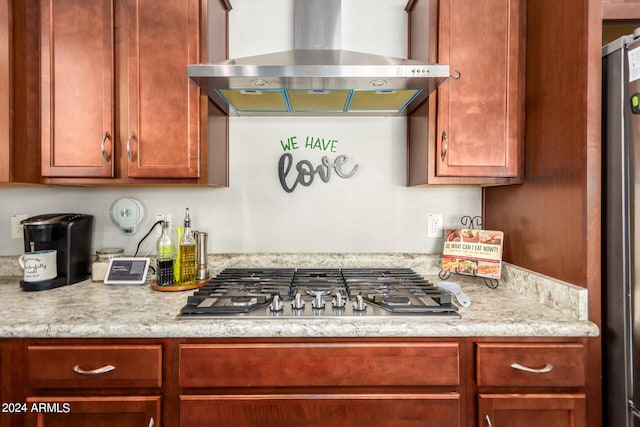 kitchen with light stone counters, stainless steel appliances, and wall chimney range hood