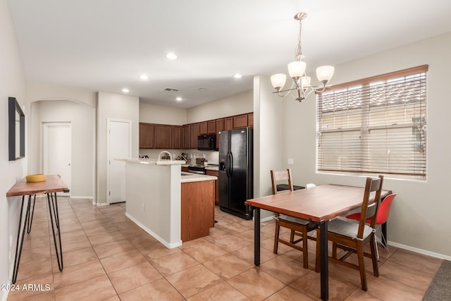 kitchen with black appliances, light tile patterned floors, a center island with sink, and hanging light fixtures