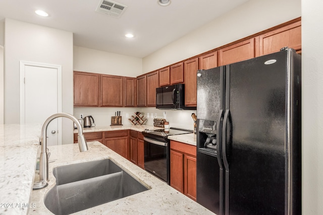 kitchen with light stone countertops, black appliances, and sink