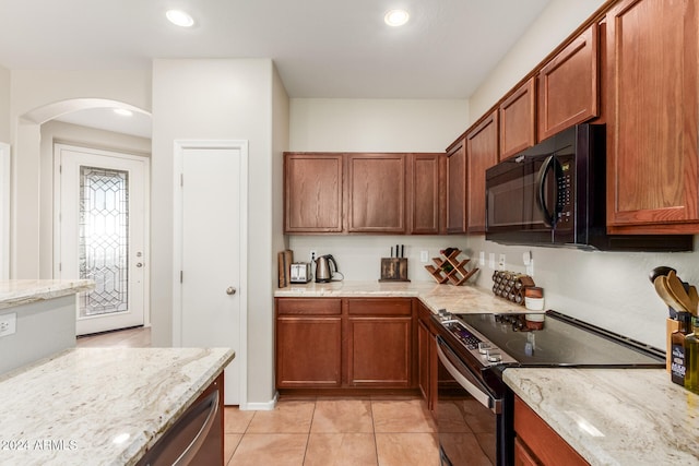 kitchen with stainless steel electric stove, light stone counters, and light tile patterned floors