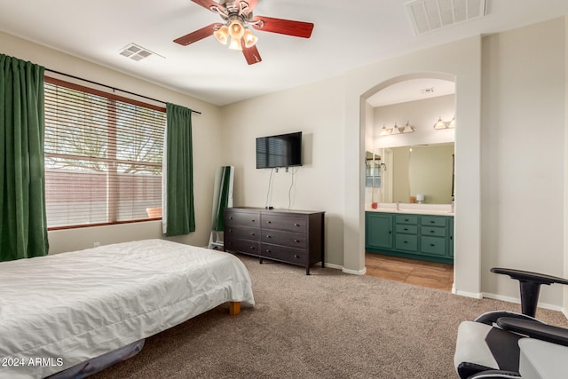 carpeted bedroom with ensuite bathroom, sink, and ceiling fan