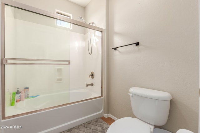 bathroom featuring toilet and bath / shower combo with glass door