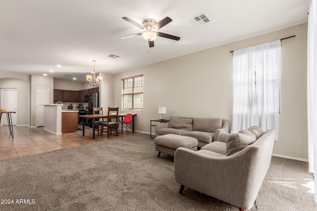 carpeted living room featuring a healthy amount of sunlight and ceiling fan with notable chandelier