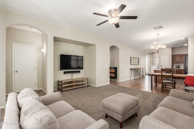 tiled living room featuring ceiling fan with notable chandelier