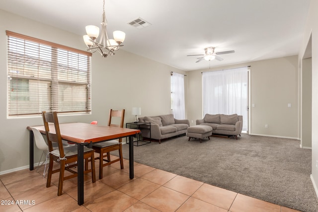 carpeted dining area featuring ceiling fan with notable chandelier