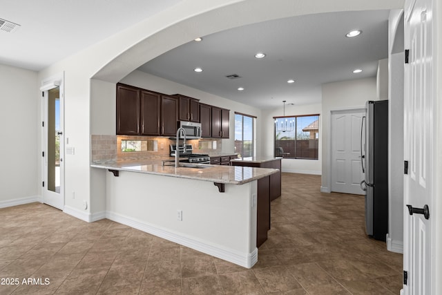 31221 N 130th Ln, Peoria, AZ 85383 - kitchen featuring stainless steel appliances, a peninsula, dark brown cabinetry, recessed lighting, and backsplash