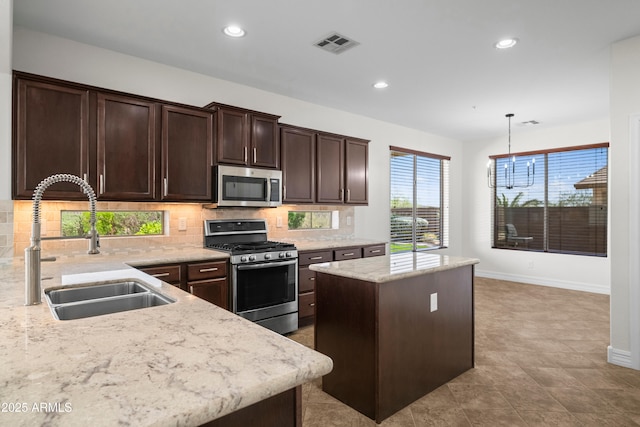 31221 N 130th Ln, Peoria, AZ 85383 - kitchen featuring stainless steel appliances, a sink, a kitchen island, dark brown cabinetry, and decorative backsplash