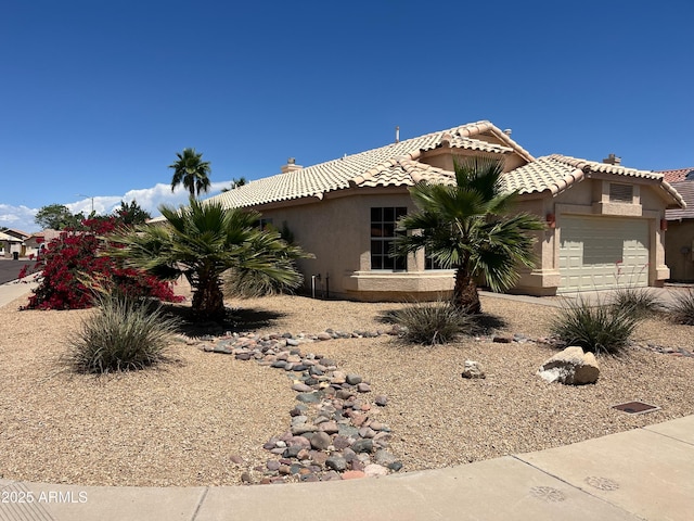 view of front facade with an attached garage, stucco siding, and a tiled roof