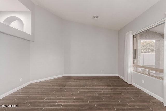 unfurnished room featuring wood finish floors, visible vents, baseboards, and lofted ceiling