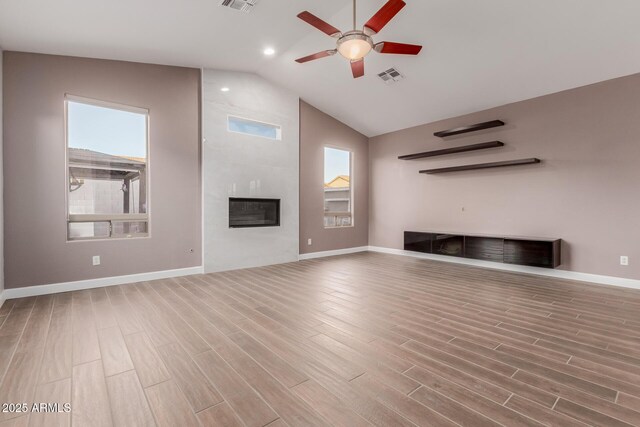 unfurnished living room with visible vents, a fireplace, lofted ceiling, and wood finished floors