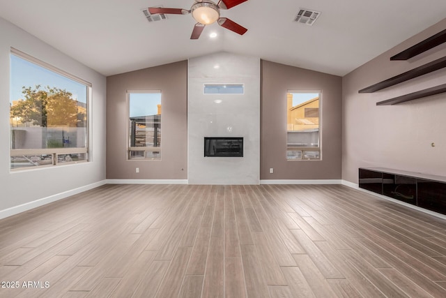 unfurnished living room with visible vents, a large fireplace, light wood finished floors, baseboards, and vaulted ceiling