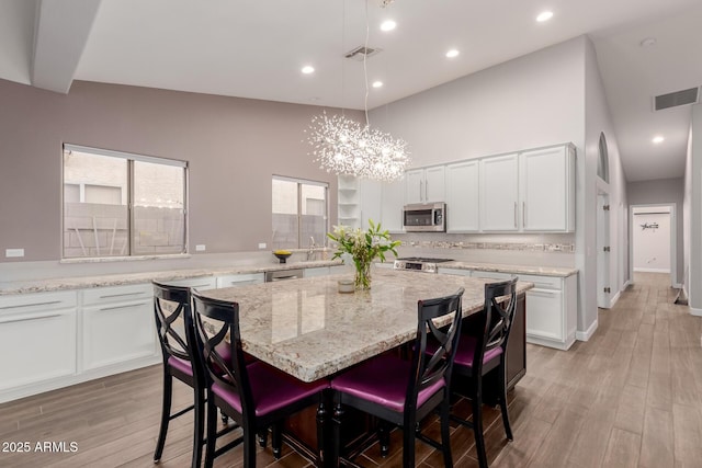 dining area with visible vents, recessed lighting, light wood-type flooring, and a towering ceiling