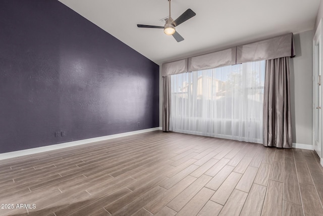 spare room featuring vaulted ceiling, baseboards, ceiling fan, and wood tiled floor