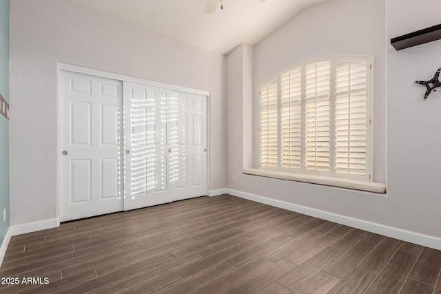 unfurnished bedroom featuring wood finish floors, baseboards, and lofted ceiling