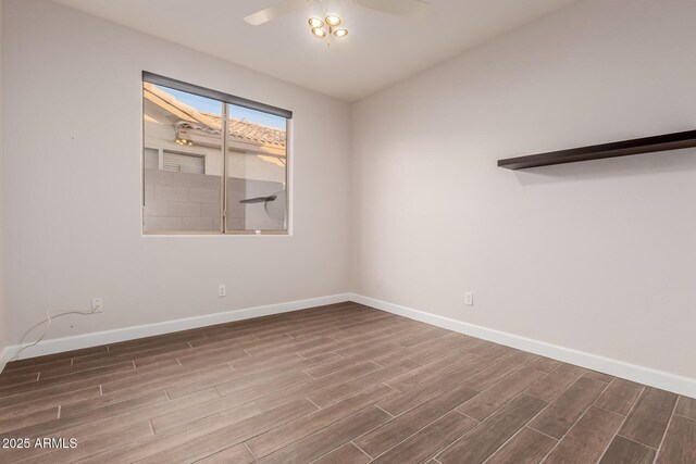 empty room featuring ceiling fan, baseboards, and wood tiled floor