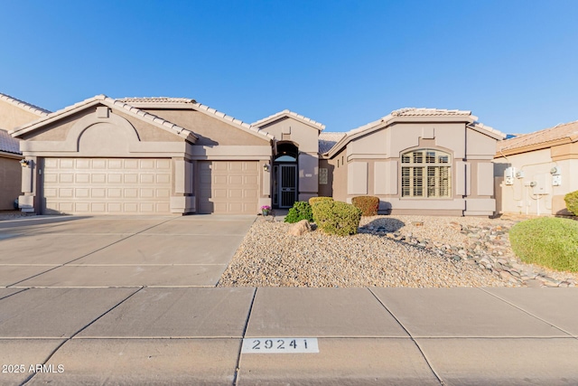 view of front of property with a tiled roof, stucco siding, driveway, and a garage