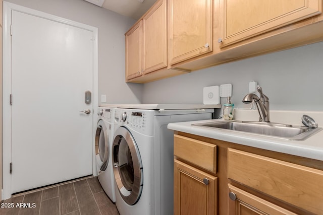 washroom with a sink, wood finish floors, cabinet space, and washer and clothes dryer