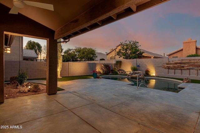 patio terrace at dusk with a fenced in pool and a fenced backyard