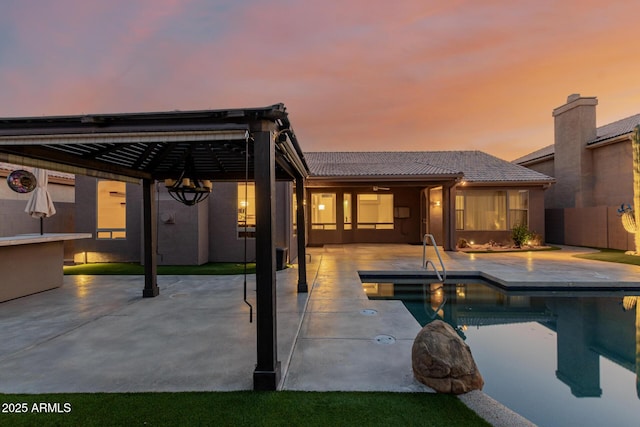 pool at dusk with a patio area, a fenced in pool, and fence