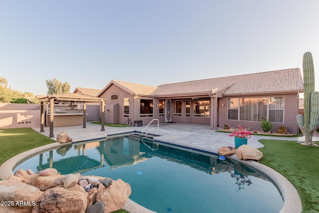 outdoor pool featuring a patio, fence, a lawn, and an outdoor kitchen