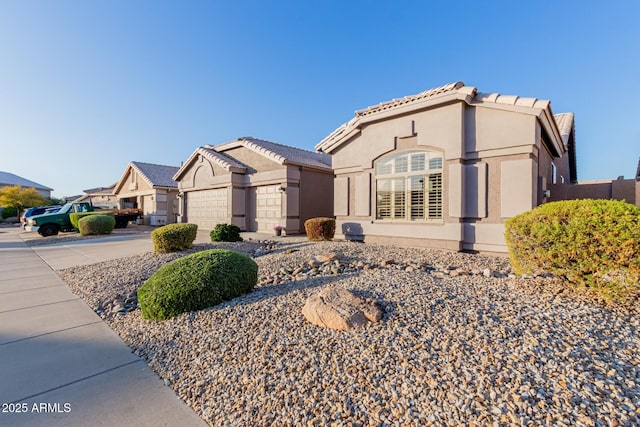 mediterranean / spanish house featuring stucco siding, a garage, concrete driveway, and a tile roof