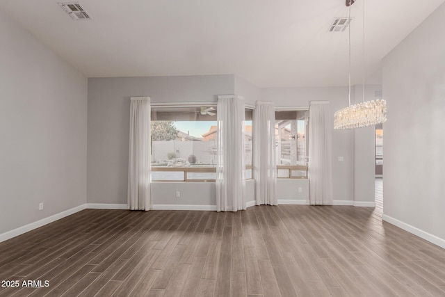 empty room featuring visible vents, baseboards, and wood finished floors