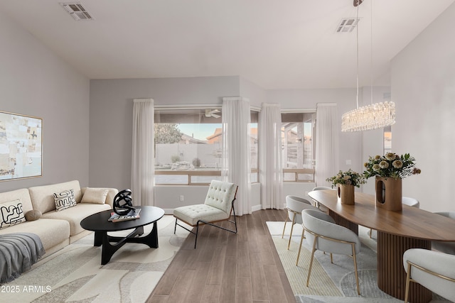 living room with a notable chandelier, visible vents, and wood finished floors