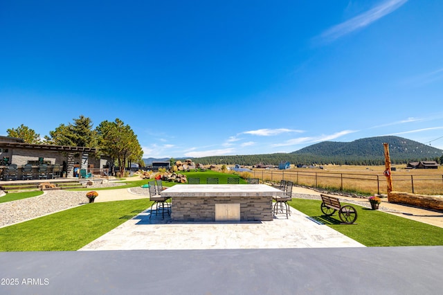 view of property's community featuring a rural view, a mountain view, a patio, and exterior bar