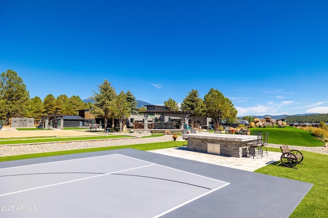 exterior space with a yard, an outdoor bar, and basketball hoop