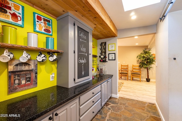 bar with a skylight and gray cabinetry