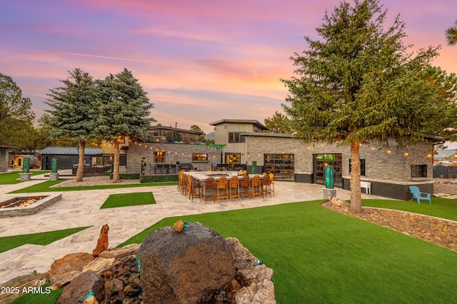 yard at dusk with exterior bar and a patio area