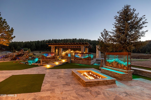 patio terrace at dusk with a fire pit and a pergola