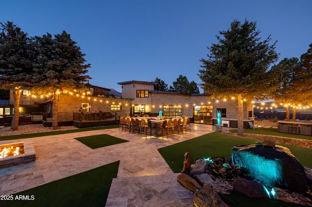 patio terrace at dusk with an outdoor bar and a fire pit