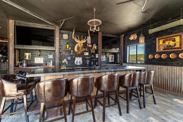 bar with hardwood / wood-style flooring and an inviting chandelier