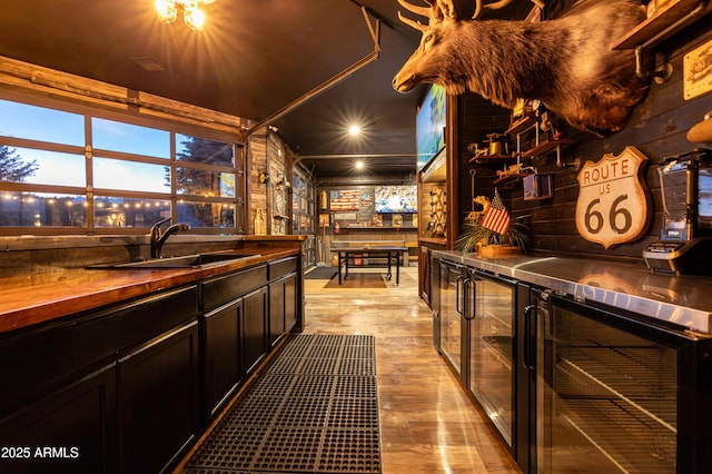 bar with sink, beverage cooler, and light wood-type flooring