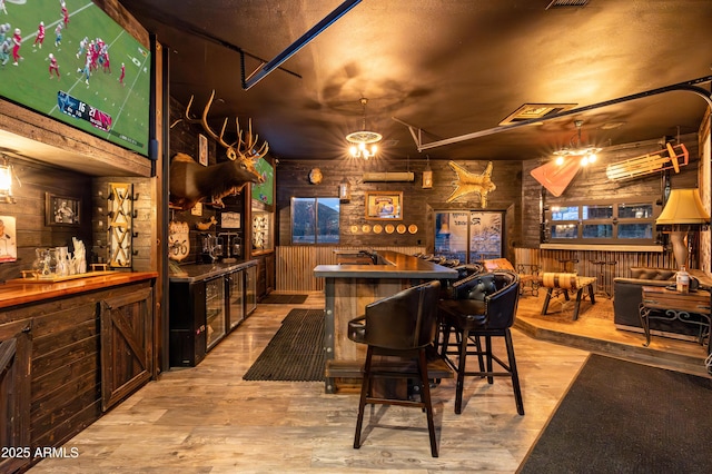 bar with wooden walls and light hardwood / wood-style floors