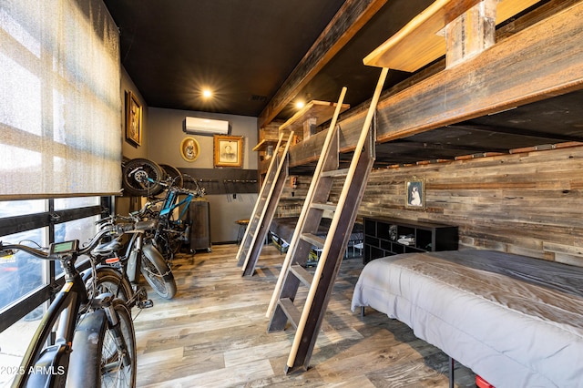 bedroom featuring wood-type flooring, a wall mounted AC, and wooden walls