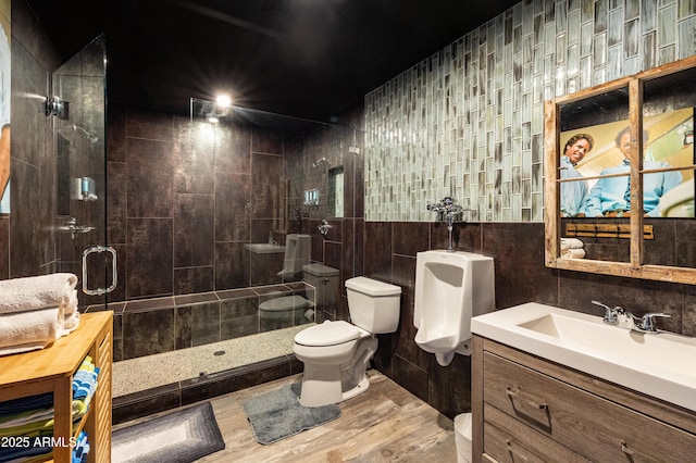 bathroom with tile walls, hardwood / wood-style floors, an enclosed shower, vanity, and toilet